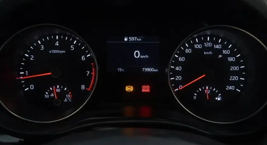 Cruscotto auto con tachimetro, contagiri e spia freno a mano accesa.