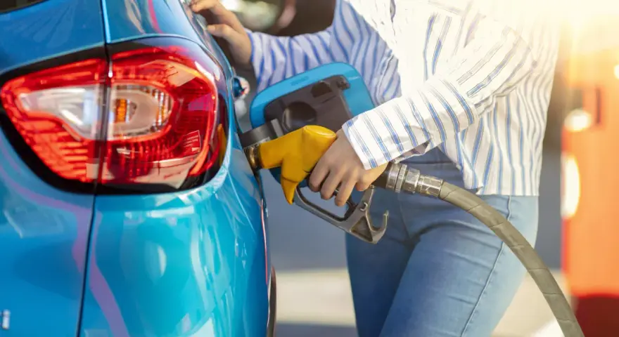 Persona fa rifornimento alla sua auto blu, pensando a come pneumatici con bassa resistenza al rotolamento migliorano l'efficienza.