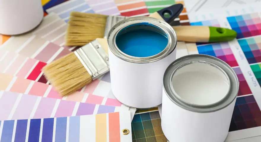 Pennelli e barattoli di vernice su campioni di colore. Una scelta di tonalità, tra cui vernice perlata o metallizzata, per il tuo prossimo progetto.