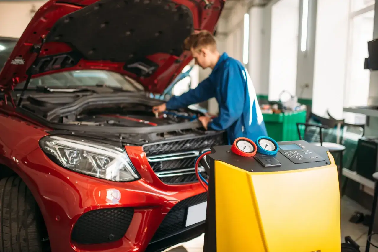 Meccanico controlla il sistema di aria condizionata auto non funziona con un'attrezzatura diagnostica.
