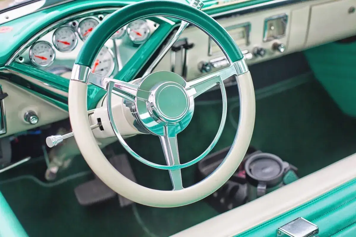 Volante d'epoca con piantone sterzo cromato e cruscotto verde acqua.