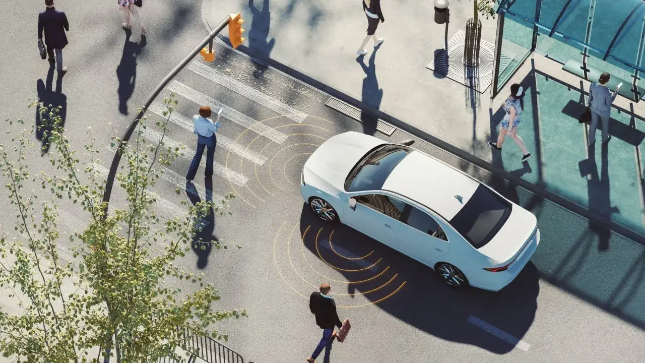 Auto elettrica bianca si avvicina a un incrocio con pedoni. Il silenzio delle auto elettriche &egrave; un nuovo rumore urbano.