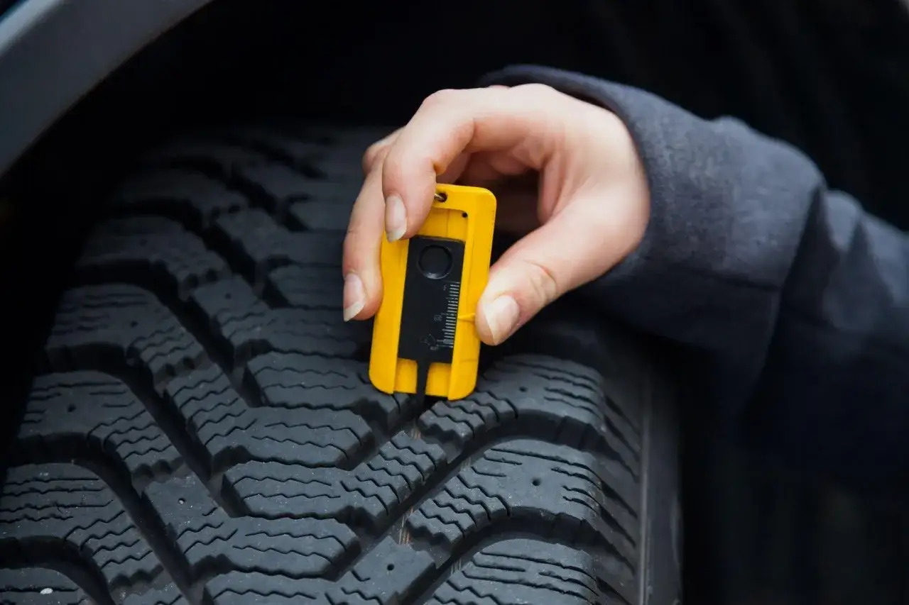 Misurazione dello spessore minimo battistrada con calibro giallo. Controllo sicurezza pneumatici.