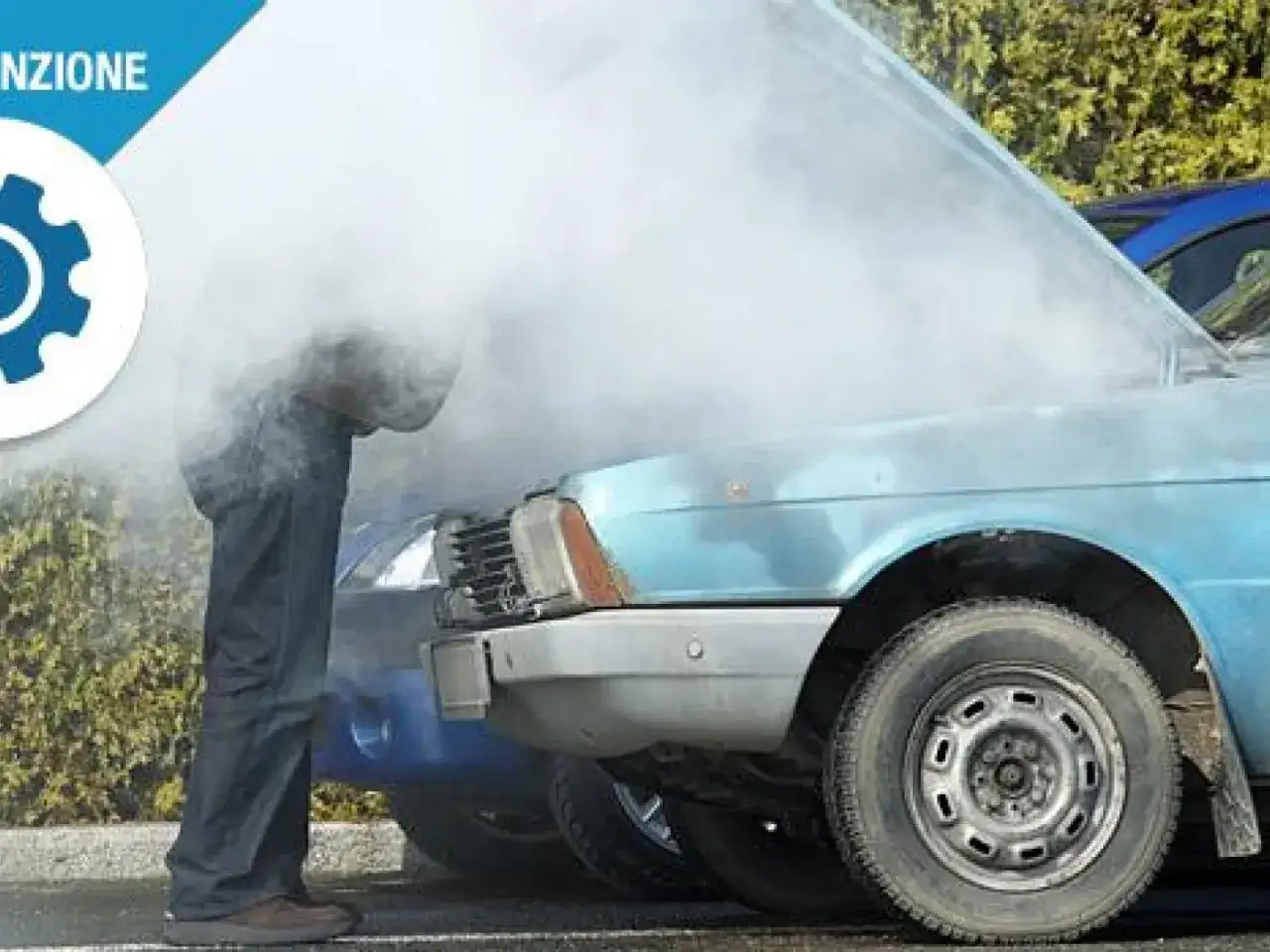 Un uomo guarda il cofano aperto di un'auto blu da cui esce molto fumo. L'auto perde acqua da ferma, un problema comune.