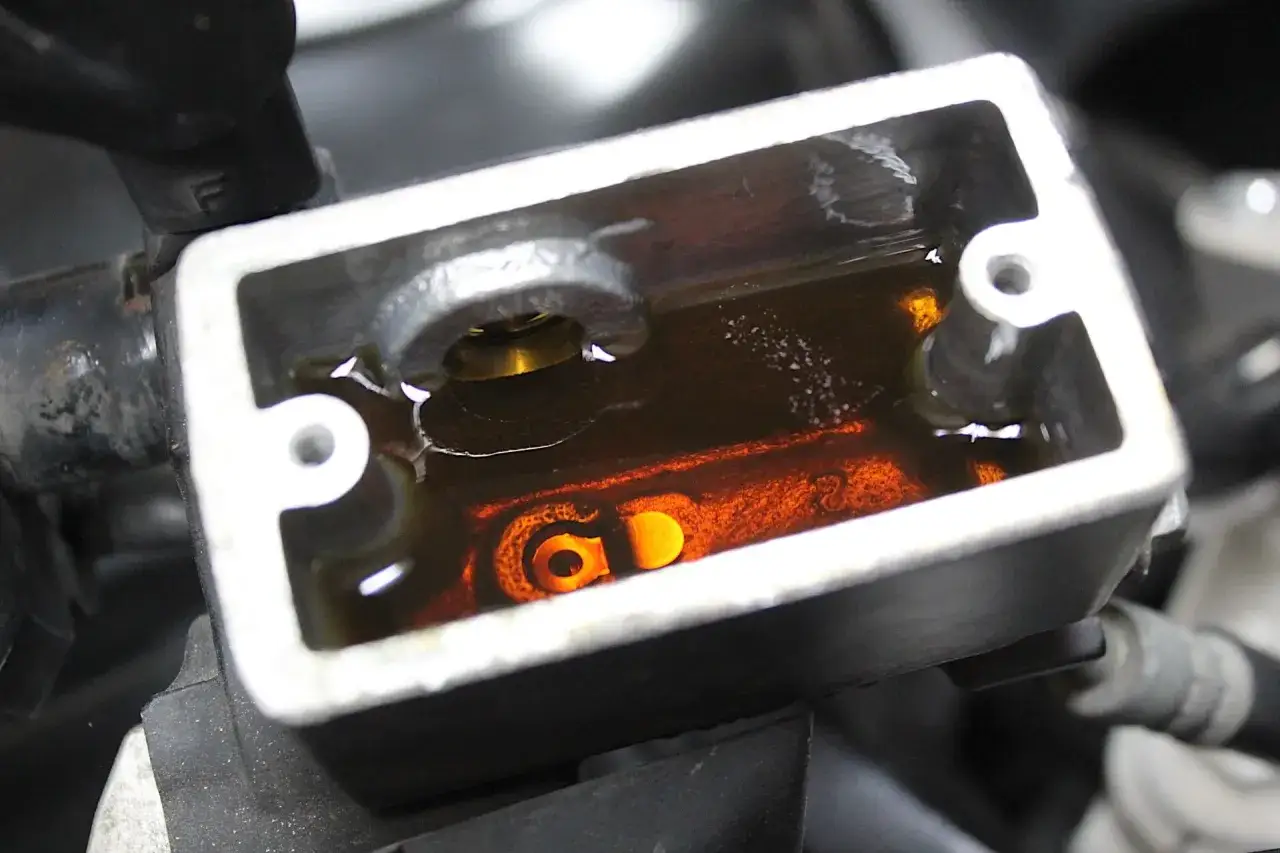 Serbatoio del liquido freni con liquido ambrato. Il livello è visibile, suggerendo un controllo di manutenzione.