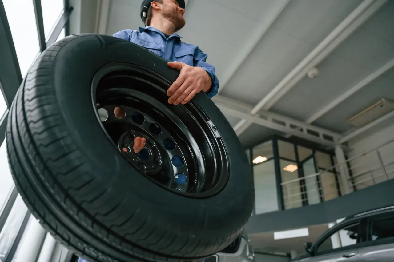 Meccanico con un pneumatico nuovo, pronto per essere montato. Che siano gomme nuove davanti o dietro, la sicurezza è fondamentale.
