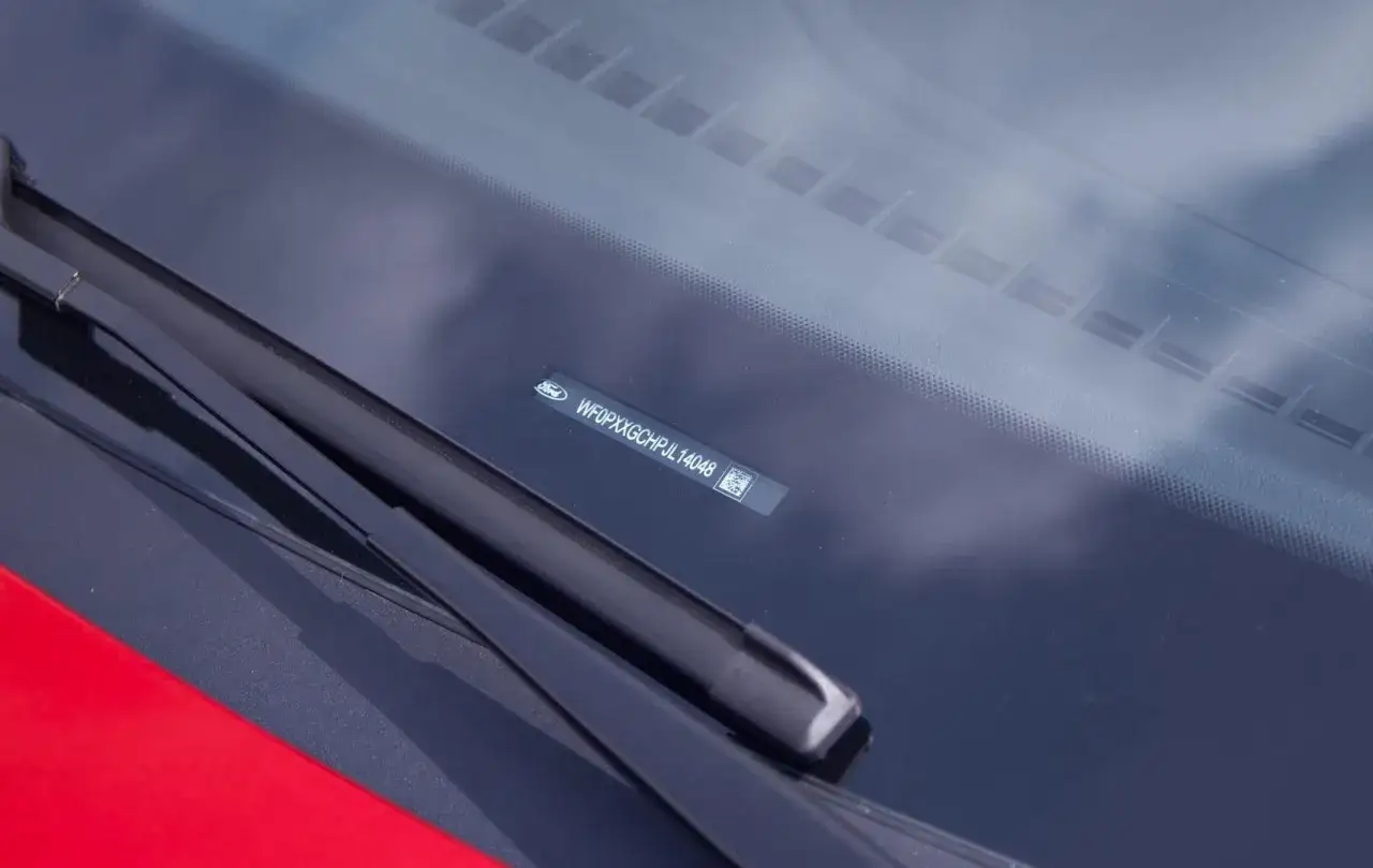 Il numero di telaio (vin auto) WF0PXXGCHPJL14048 è visibile sul parabrezza di un'auto Ford rossa.