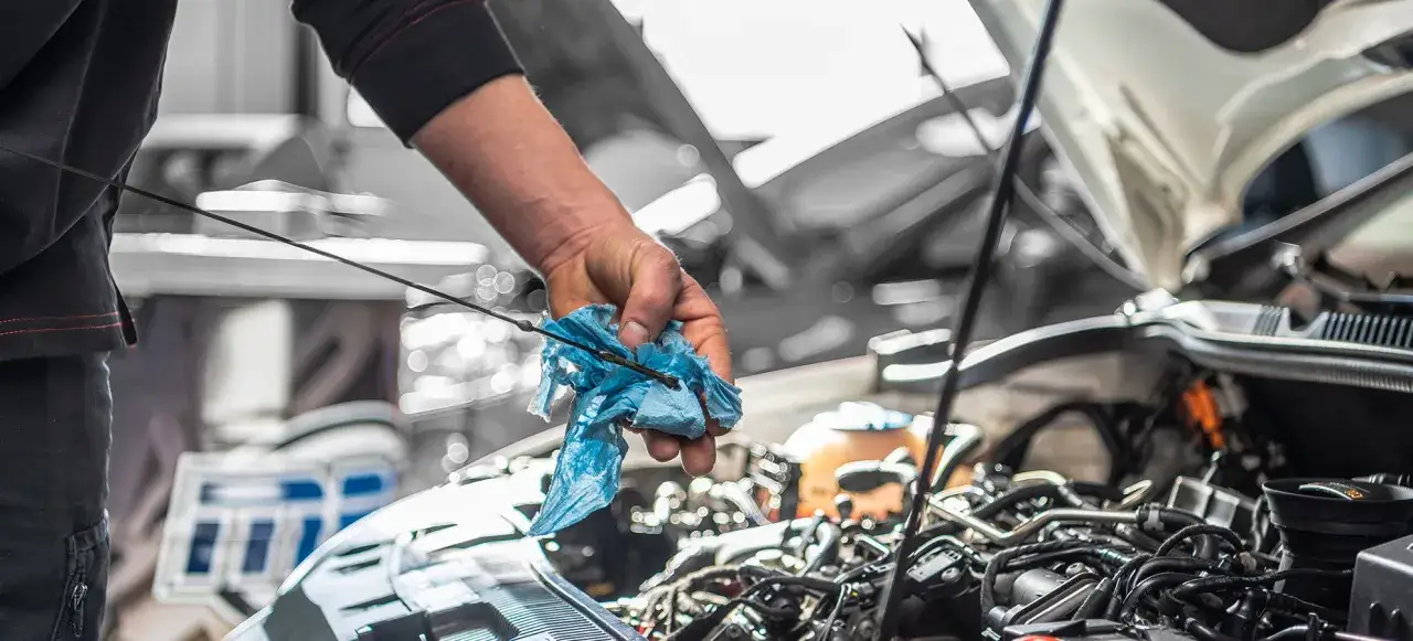 Meccanico controlla l'olio motore, forse per capire perché la macchina consuma troppo gasolio.