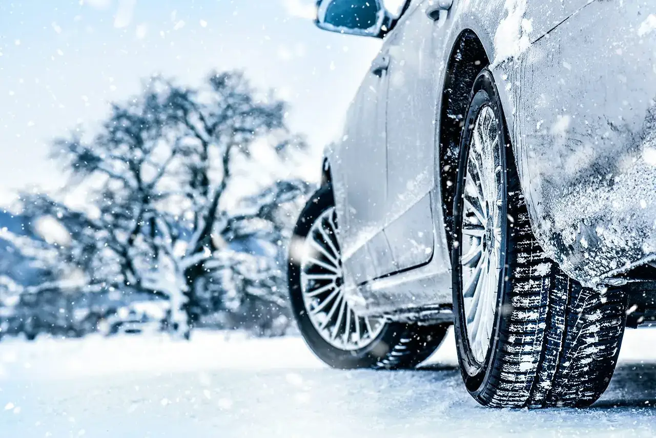 Auto elettrica su strada innevata, con pneumatici invernali che garantiscono aderenza.