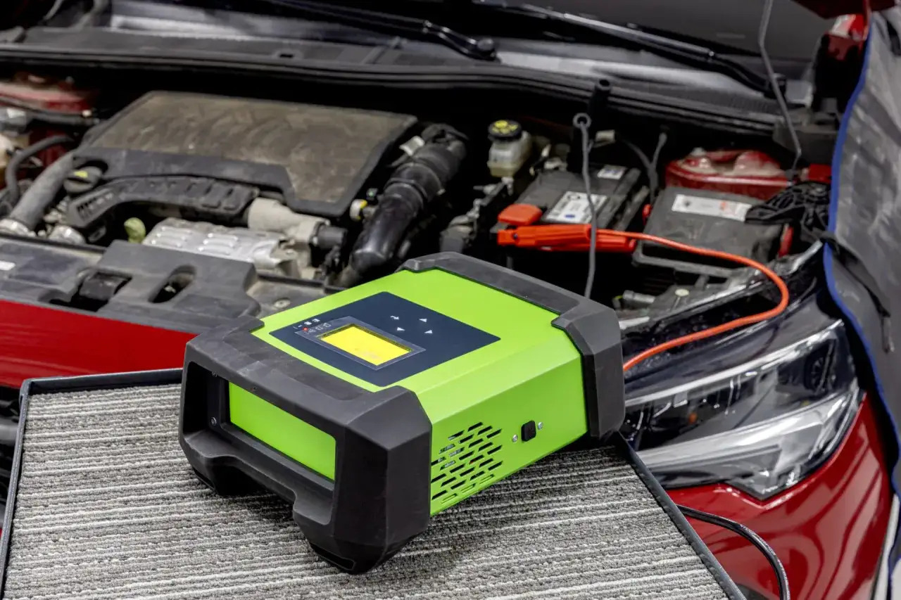 Caricabatterie verde collegato alla batteria di un'auto. Utile quando la batteria si scarica a vettura ferma.