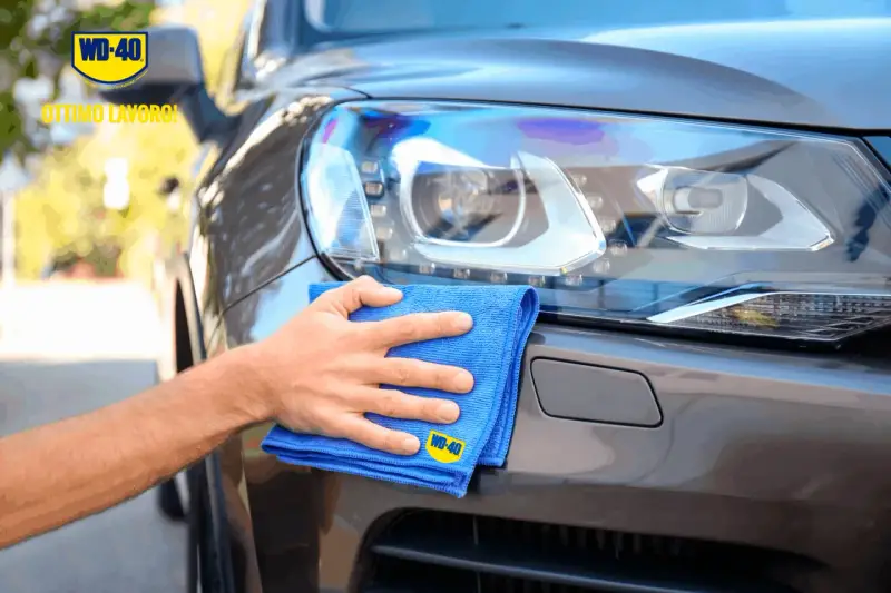 Mano che lucida fari auto con WD-40 e panno blu. Ottimo lavoro!
